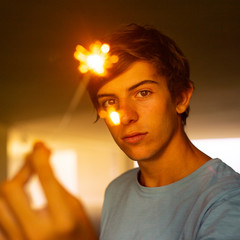 Indoor photo of young beautiful happy smiling boy holding sparkler, Model looking at camera.