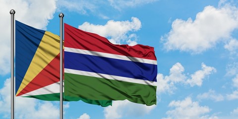 Seychelles and Gambia flag waving in the wind against white cloudy blue sky together. Diplomacy concept, international relations.