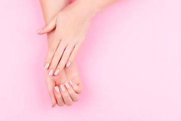 Obraz na płótnie Canvas Beautiful Woman Hands on pink backgrounda. Spa and Manicure concept. Female hands with pink manicure. Soft skin skincare concept. Beauty nails.