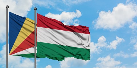 Fototapeta na wymiar Seychelles and Hungary flag waving in the wind against white cloudy blue sky together. Diplomacy concept, international relations.