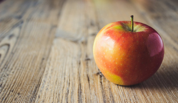 mela rossa singola su fondo legno