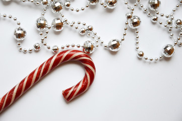 Silver beads for interior decoration on a white background. Decorations for the holiday. merry Christmas and happy New year. And Christmas candy with red and white stripes.