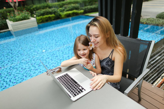 beautiful mother and daughter using laptop on background of swim