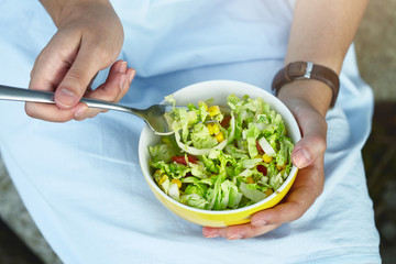 Obraz na płótnie Canvas young woman holding bowl with tasty fresh green vegetable salad, healthy food, vegan breakfast meal