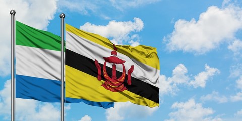 Sierra Leone and Brunei flag waving in the wind against white cloudy blue sky together. Diplomacy concept, international relations.