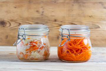 Korean carrots and fermented cabbage in glass jars on a wooden table