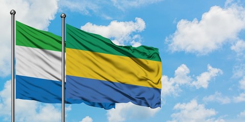 Sierra Leone and Gabon flag waving in the wind against white cloudy blue sky together. Diplomacy concept, international relations.