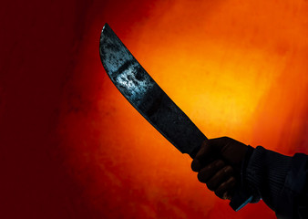 hand with scary machete in the dark on red background - obrazy, fototapety, plakaty
