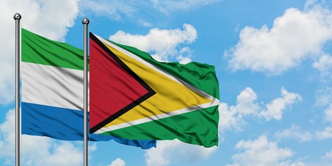 Sierra Leone and Guyana flag waving in the wind against white cloudy blue sky together. Diplomacy concept, international relations.