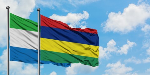 Sierra Leone and Mauritius flag waving in the wind against white cloudy blue sky together. Diplomacy concept, international relations.