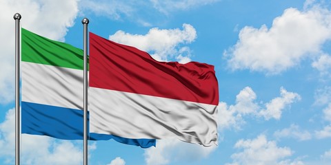 Sierra Leone and Monaco flag waving in the wind against white cloudy blue sky together. Diplomacy concept, international relations.