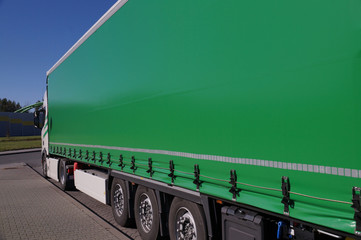 View of the green tarpaulin covering the semi-trailer of the truck. Truck transport. - obrazy, fototapety, plakaty
