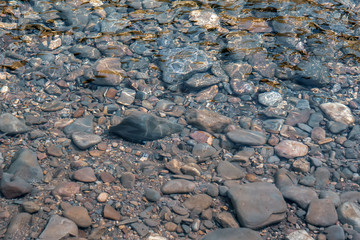 Stones under water on the riverbank, clear water in the river