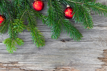 Christmas background on a wooden rustic old table with fir branches and red Christmas decorations.