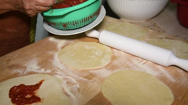 Feminine hands make Apulian panzerotti pies with tomato, mozzarella and prosciutto cotto. Panzerotti is a traditional dish in Salento, Puglia, Italy, fried in olive oil
