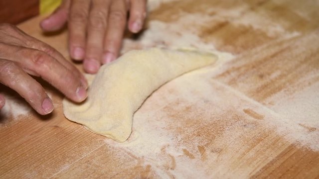Feminine hands make Apulian panzerotti pies with tomato, mozzarella and prosciutto cotto. Panzerotti is a traditional dish in Salento, Puglia, Italy, fried in olive oil