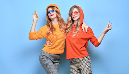 Two easy-going happy hipster Woman smiling, Stylish fashion orange colored outfit. Beautiful Girl...