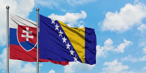 Slovakia and Bosnia Herzegovina flag waving in the wind against white cloudy blue sky together....