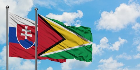 Slovakia and Guyana flag waving in the wind against white cloudy blue sky together. Diplomacy concept, international relations.