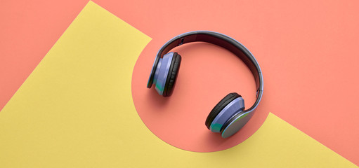 Minimal fashion, Trendy headphones. Music vibration on coral geometry background. Hipster DJ accessory Flat lay. Art creative summer vibes fashionable pop art style. Sweet pastel design color