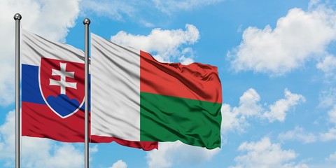 Slovakia and Madagascar flag waving in the wind against white cloudy blue sky together. Diplomacy concept, international relations.