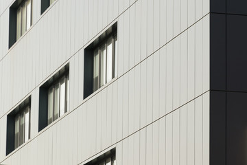 Fototapeta premium Geometryczne elementy kolorystyczne elewacji budynku z płaszczyznami, liniami, narożnikami z akcentami i refleksami dla abstrakcyjnego tła i faktury w kolorach białym, szarym, niebieskim. Miejsce na tekst