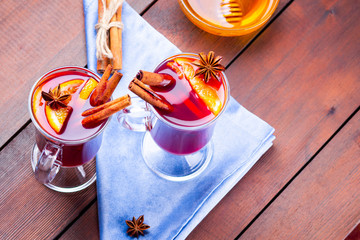 Mulled wine with spices and honey on wooden background. Christmas mulled wine with orange, star...