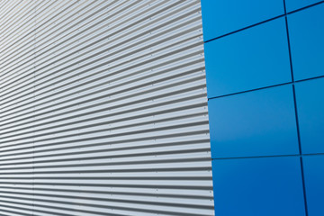 Geometric colored building facade elements with planes, lines and corners with light flare and reflections for an abstract background and texture of white, blue, gray colors. Place for text