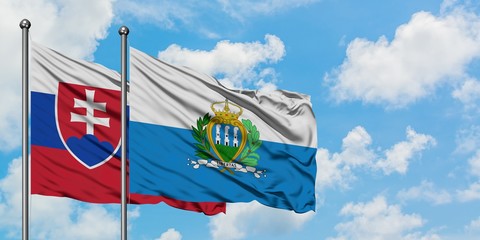 Slovakia and San Marino flag waving in the wind against white cloudy blue sky together. Diplomacy concept, international relations.