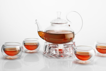 glass teapot on glass stand heated by candle on white background, black tea in glass teapot isolated on white background