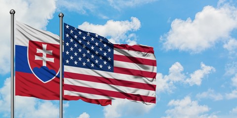 Slovakia and United States flag waving in the wind against white cloudy blue sky together. Diplomacy concept, international relations.