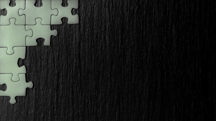 Silver puzzle in the corner of the image on a black natural stone background of slate. A frame with an empty space for your description.