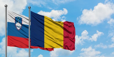 Slovenia and Chad flag waving in the wind against white cloudy blue sky together. Diplomacy concept, international relations.