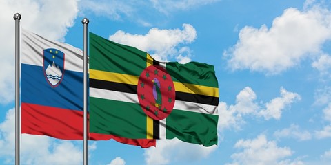 Slovenia and Dominica flag waving in the wind against white cloudy blue sky together. Diplomacy concept, international relations.
