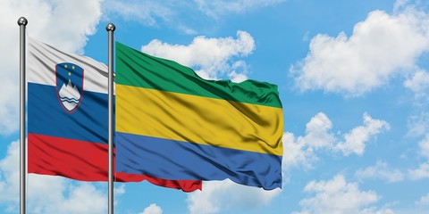 Slovenia and Gabon flag waving in the wind against white cloudy blue sky together. Diplomacy concept, international relations.