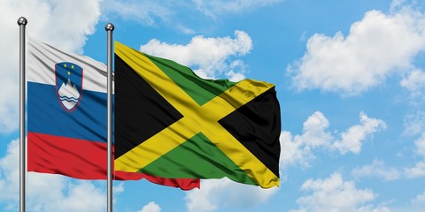 Slovenia and Jamaica flag waving in the wind against white cloudy blue sky together. Diplomacy concept, international relations.