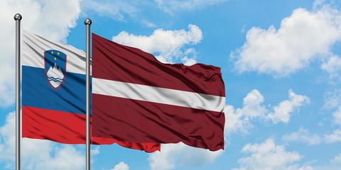 Slovenia and Latvia flag waving in the wind against white cloudy blue sky together. Diplomacy concept, international relations.