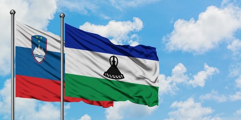 Slovenia and Lesotho flag waving in the wind against white cloudy blue sky together. Diplomacy concept, international relations.