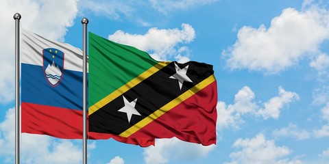 Slovenia and Saint Kitts And Nevis flag waving in the wind against white cloudy blue sky together. Diplomacy concept, international relations.