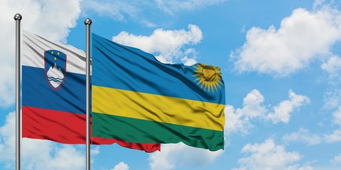Slovenia and Rwanda flag waving in the wind against white cloudy blue sky together. Diplomacy concept, international relations.