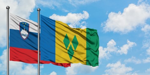 Slovenia and Saint Vincent And The Grenadines flag waving in the wind against white cloudy blue sky together. Diplomacy concept, international relations.