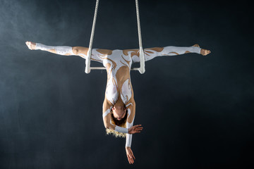 A young girl performs the acrobatic elements in the air trapeze. Studio shooting performances on a...
