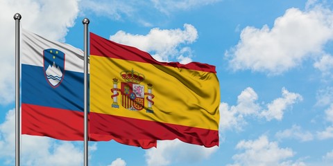 Slovenia and Spain flag waving in the wind against white cloudy blue sky together. Diplomacy concept, international relations.