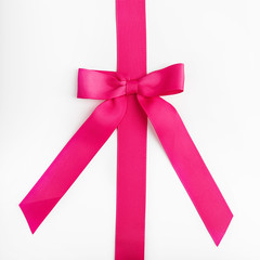 Pink ribbon with bow on white background.
