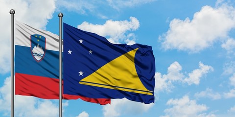 Slovenia and Tokelau flag waving in the wind against white cloudy blue sky together. Diplomacy concept, international relations.
