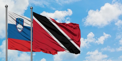 Slovenia and Trinidad And Tobago flag waving in the wind against white cloudy blue sky together. Diplomacy concept, international relations.