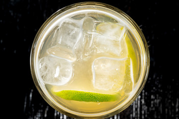 Alcoholic cocktail with limes in a glass on a dark background.