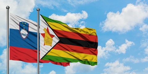 Slovenia and Zimbabwe flag waving in the wind against white cloudy blue sky together. Diplomacy concept, international relations.
