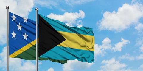 Solomon Islands and Bahamas flag waving in the wind against white cloudy blue sky together. Diplomacy concept, international relations.