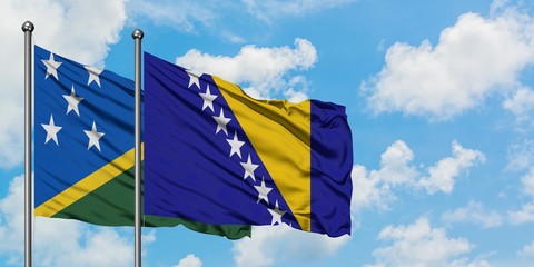 Solomon Islands and Bosnia Herzegovina flag waving in the wind against white cloudy blue sky together. Diplomacy concept, international relations.